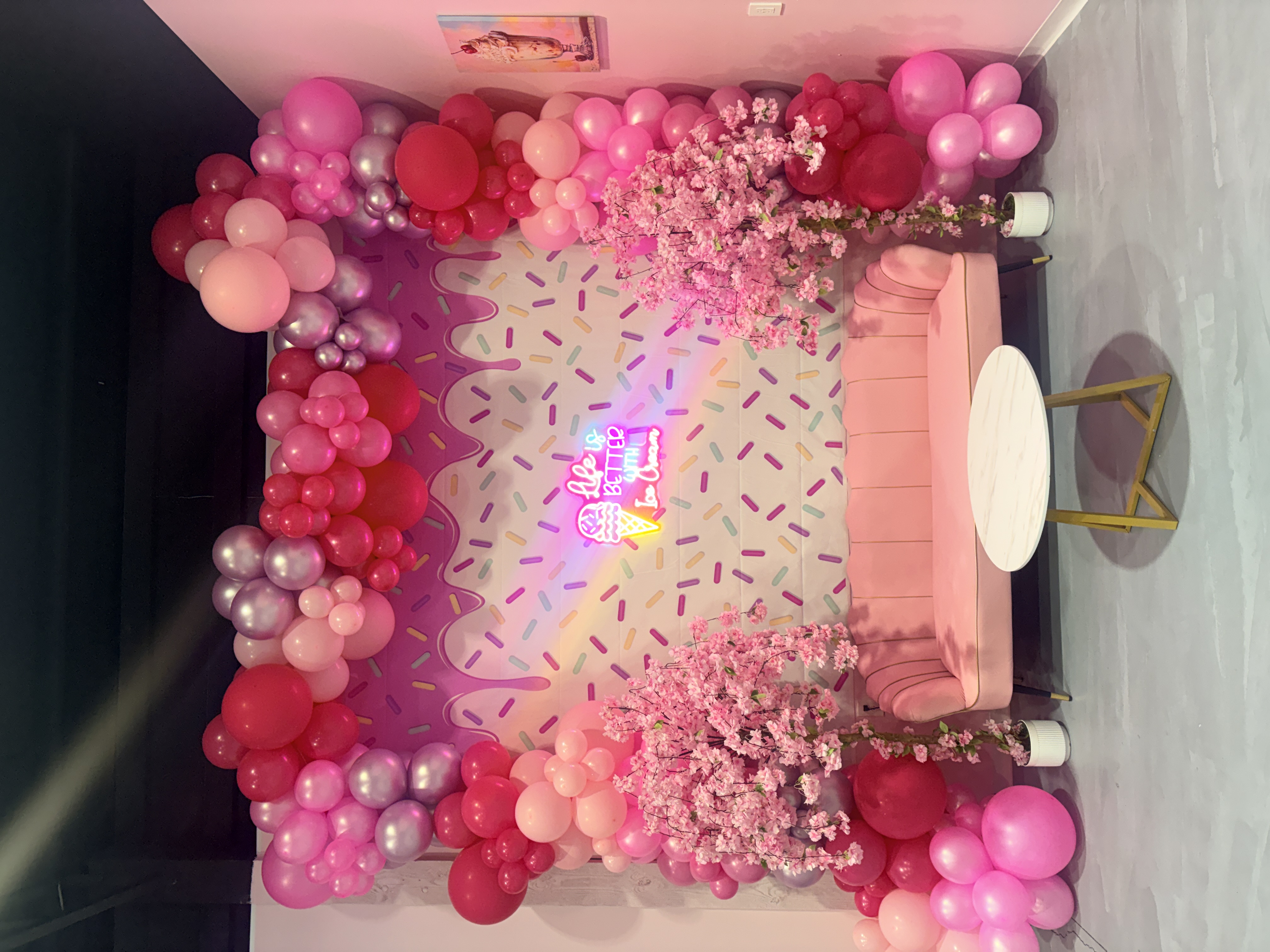Photo op corner with neon sign and pink couch at Sweet Swirls